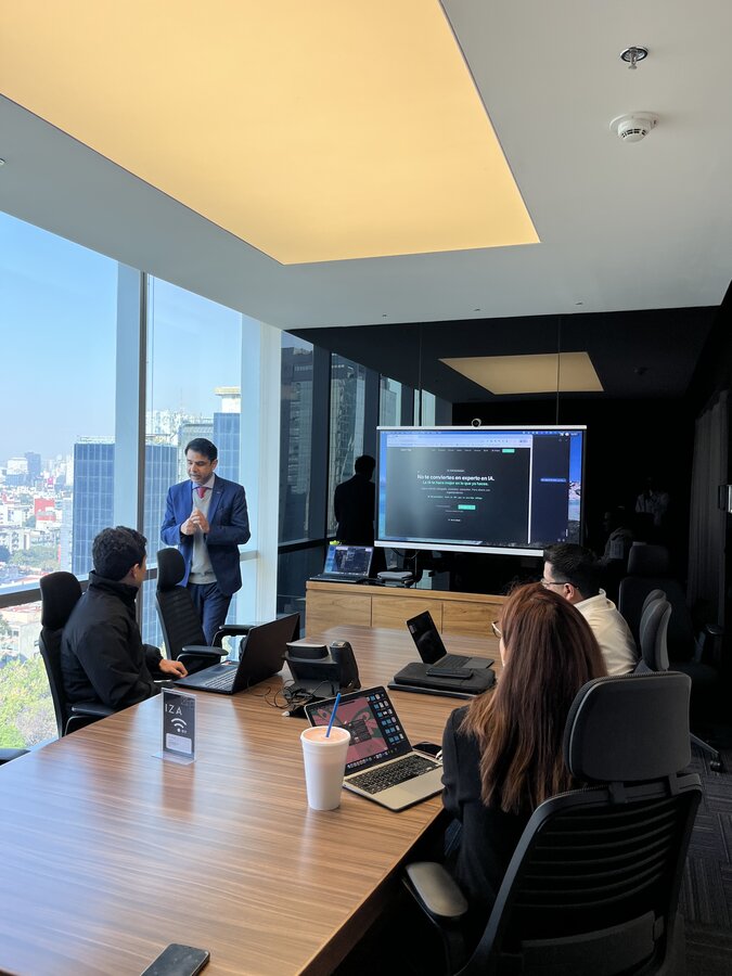 Ashish presenting AI live in a high-floor Mexico City boardroom, his hero line on screen and the city skyline behind